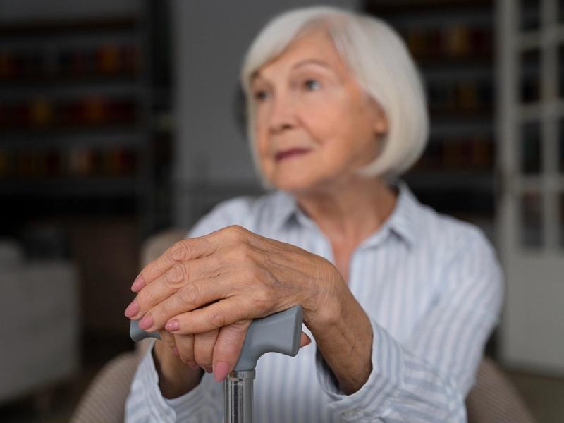 Elderly woman with cane, thoughtful expression
