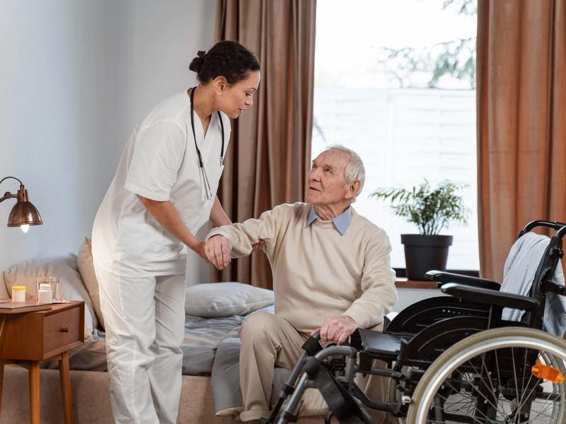 Caregiver assisting an elderly man in a room