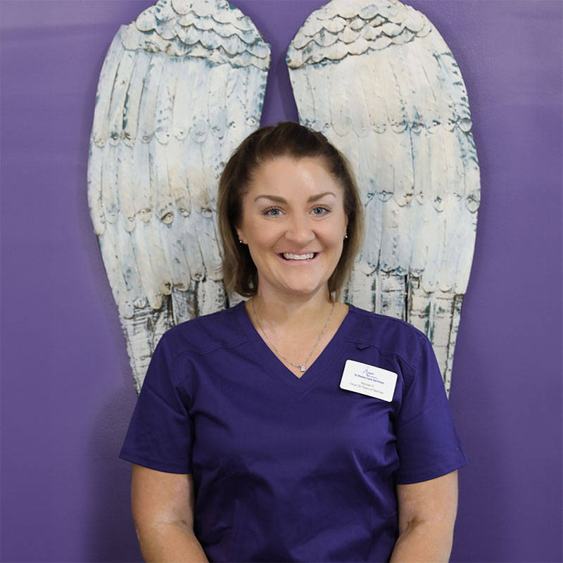 Staff member posing in front of decorative angel wings.