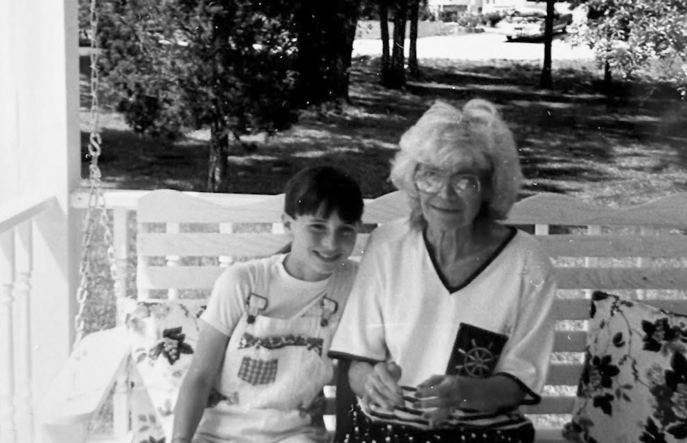 An older woman and a young girl on a porch swing.