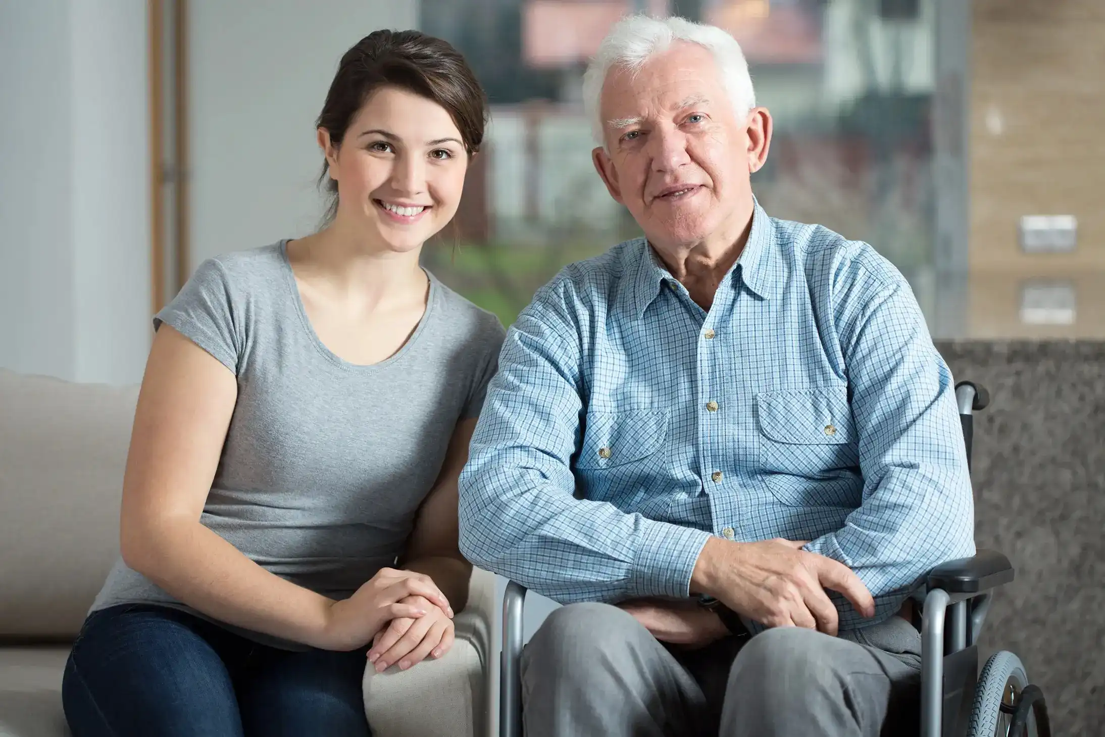 Smiling staff member with a resident in a common area.