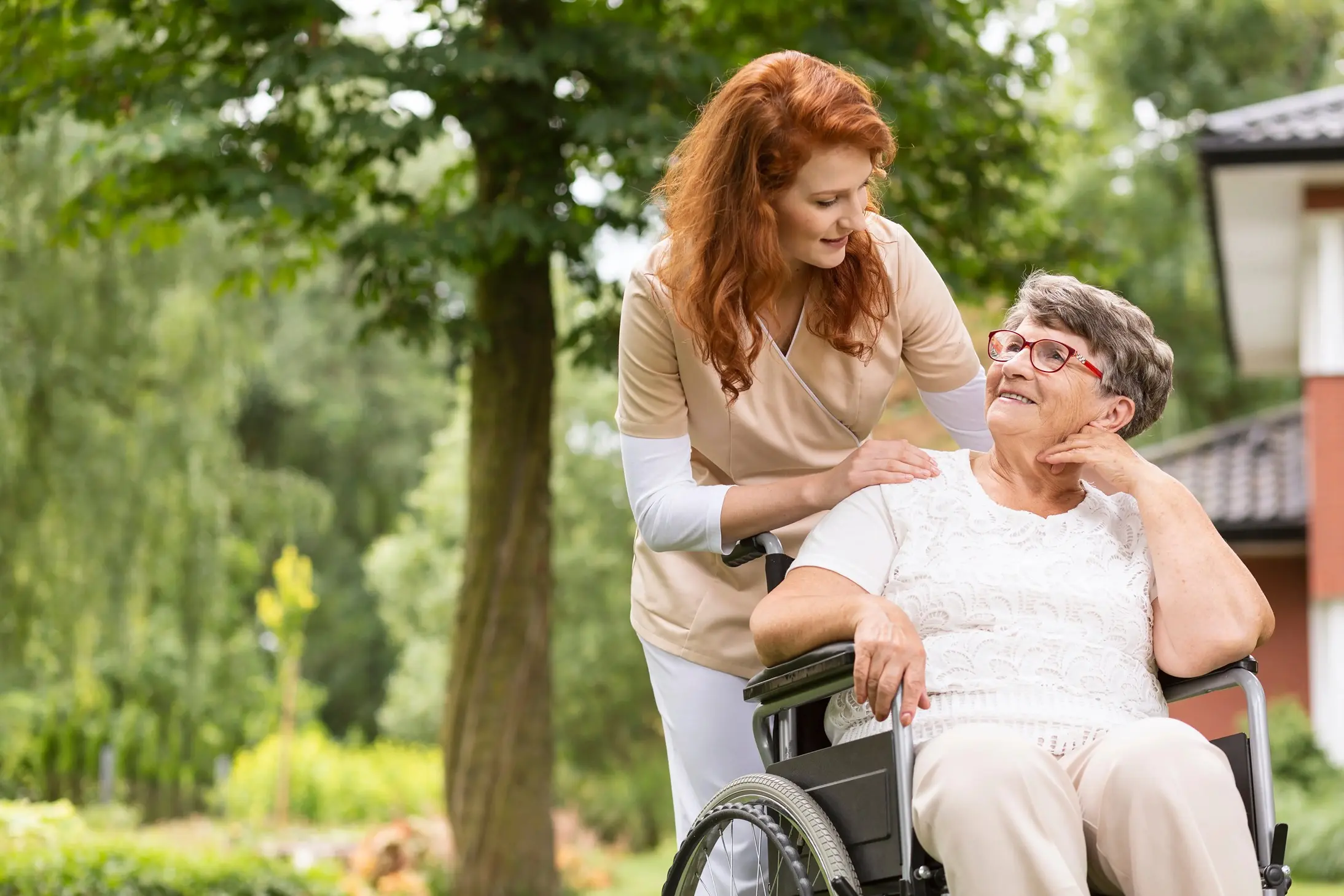 A caregiver with a resident in a garden setting.