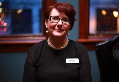 Staff member posing indoors with a name tag