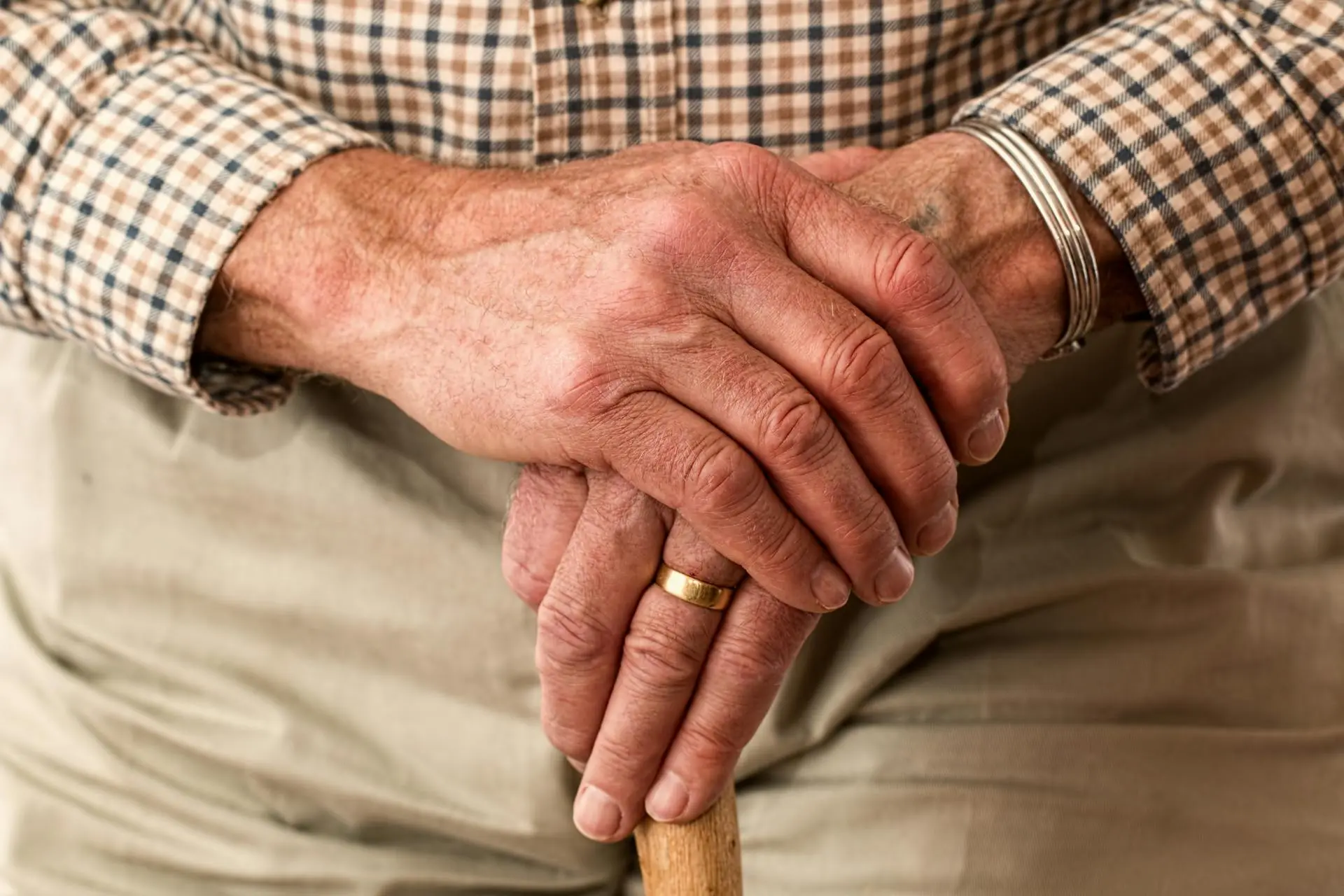 Close-up of an elderly person's hands with a cane