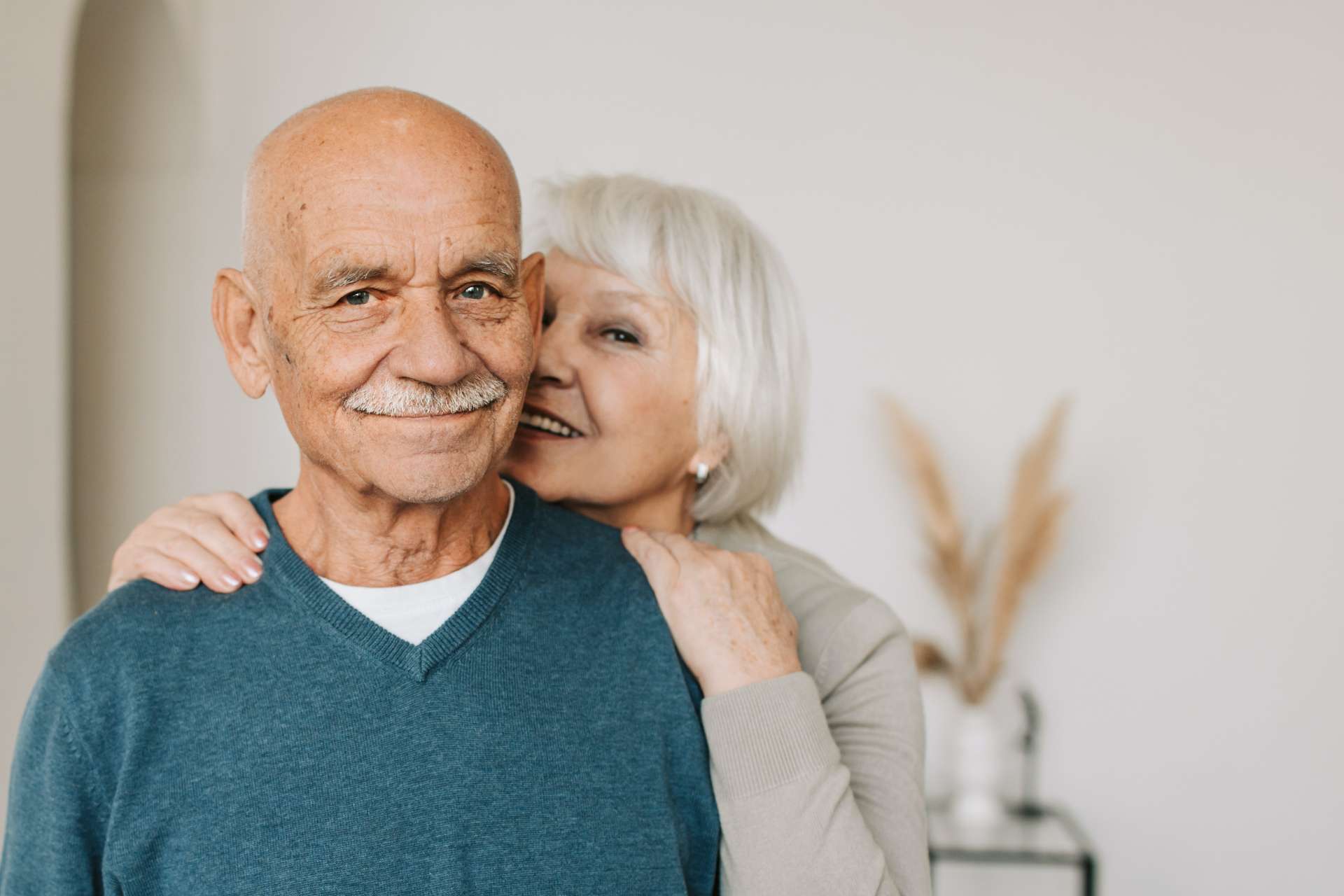 A smiling elderly couple in a warm interior setting.
