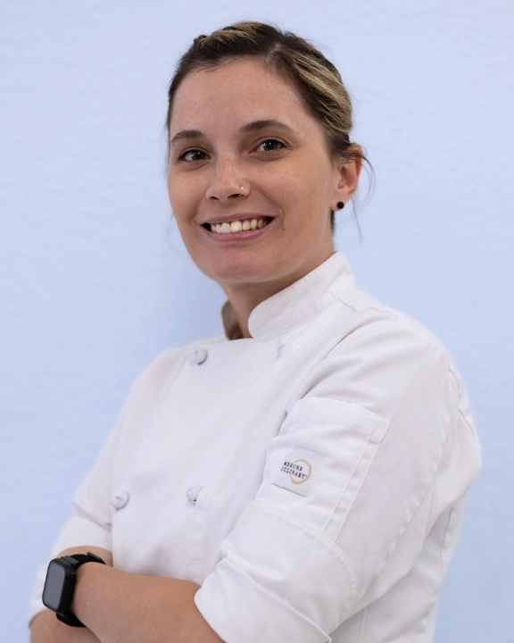 Chef smiling in a professional kitchen setting.