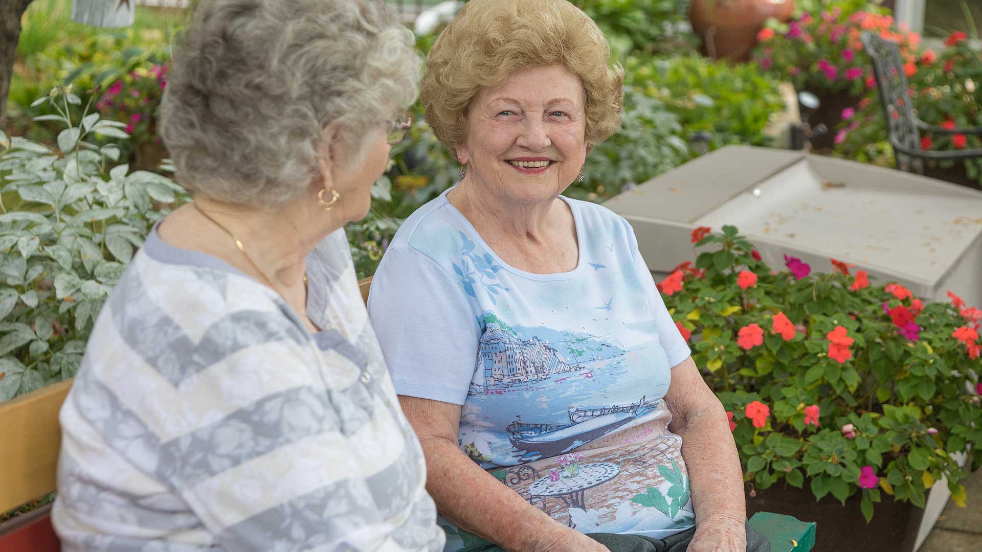 Two smiling residents in a garden setting.