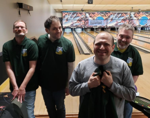 Group of men in matching shirts at a bowling alley