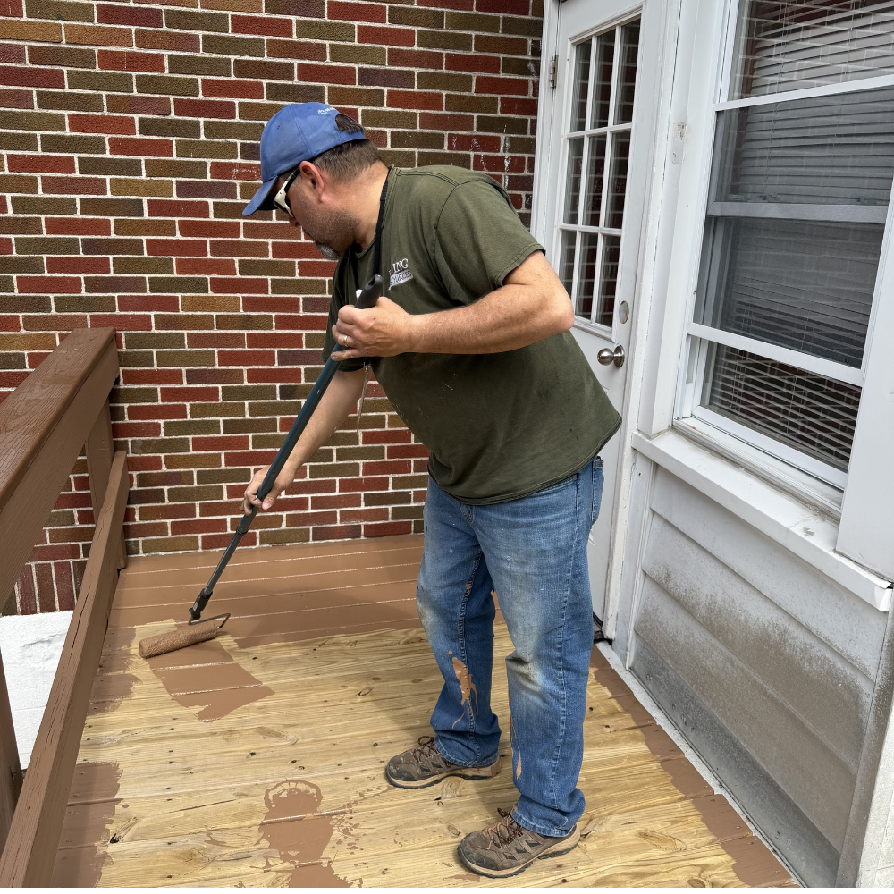 Maintenance worker painting a deck
