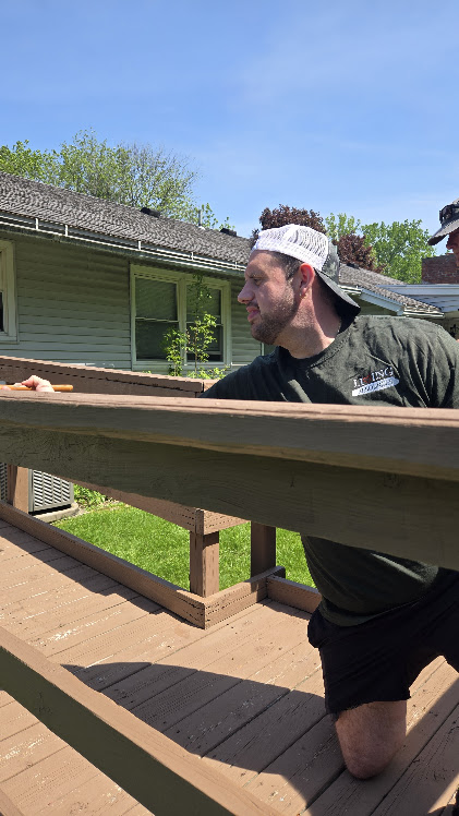 Man painting a wooden deck in an outdoor space