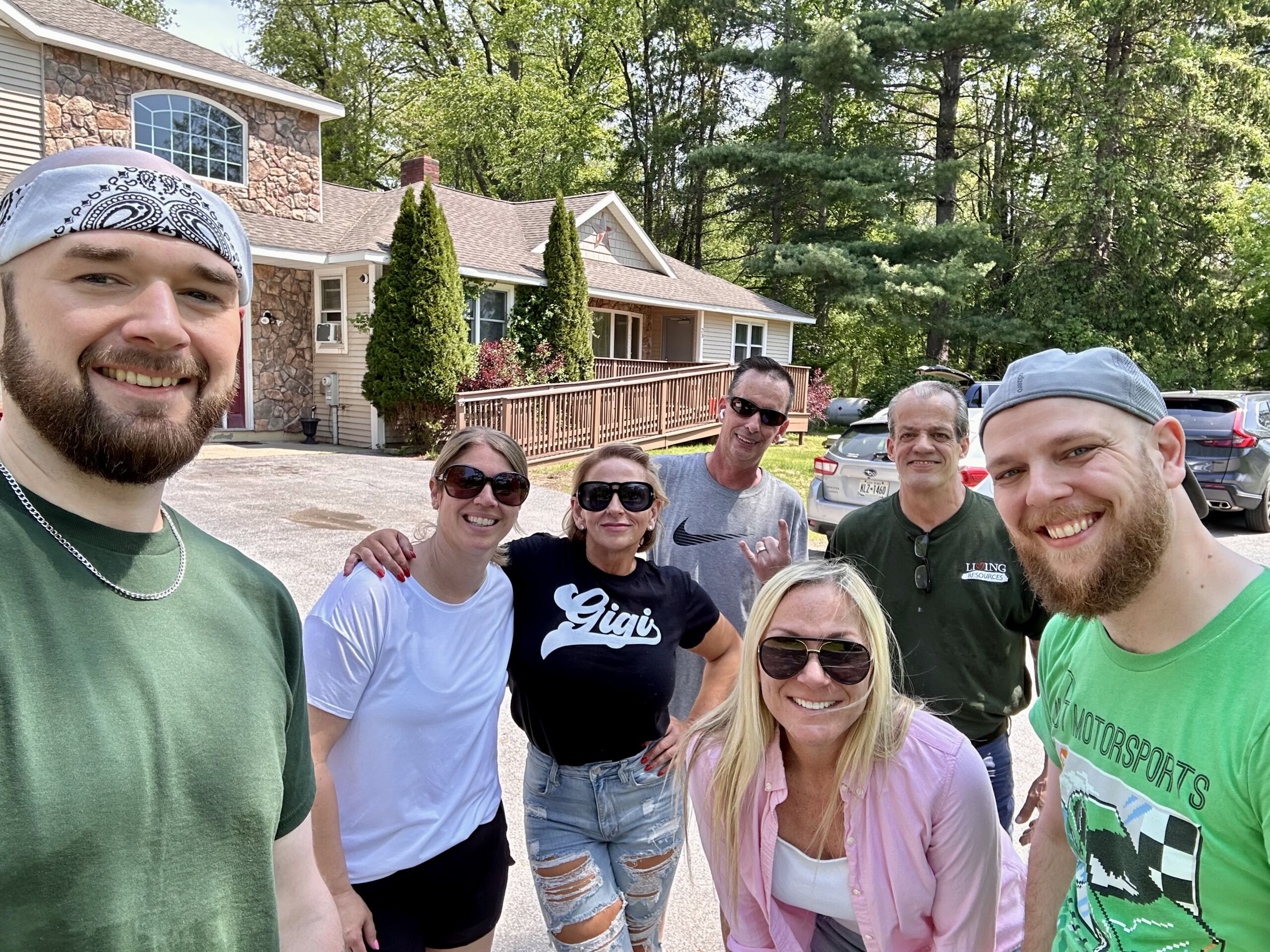 Group of staff and residents smiling outside the facility.