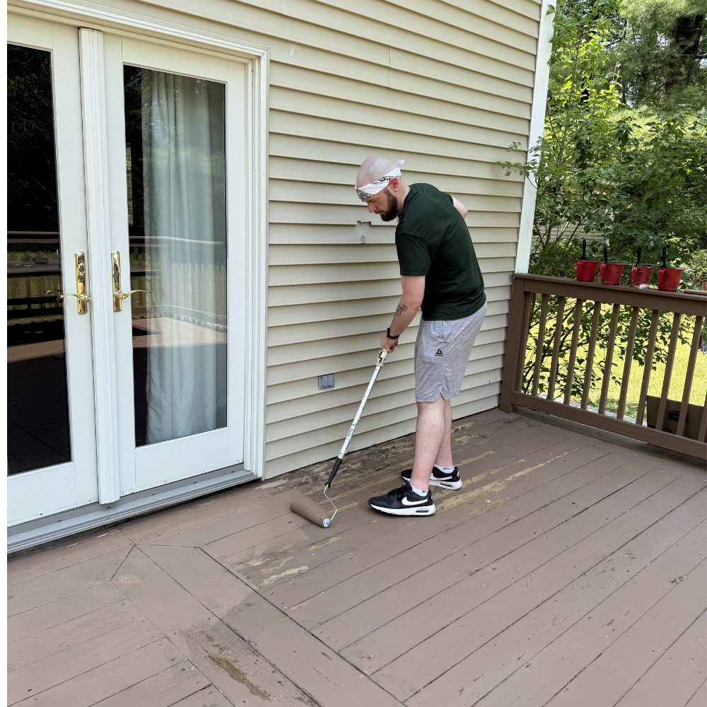 Person painting a wooden deck outside a building