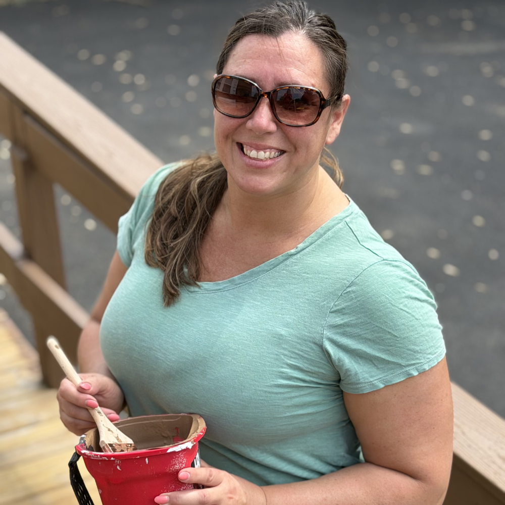 Woman smiling while painting outdoors.
