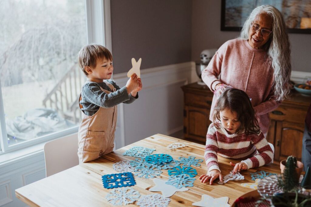 Children and an elder making crafts together indoors.