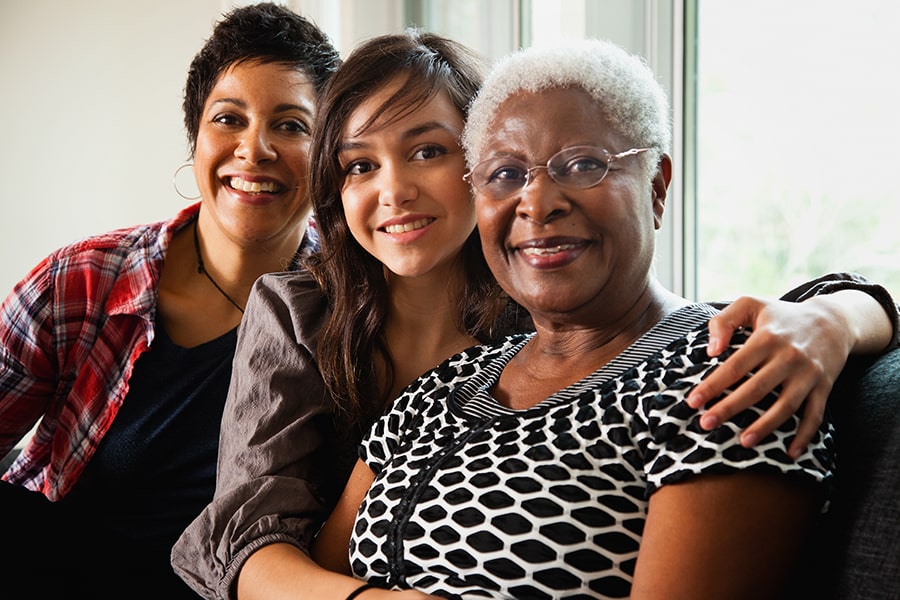 Three women smiling together indoors.