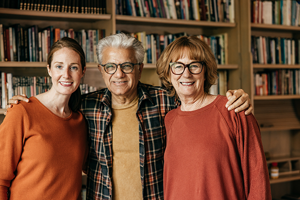 Three smiling individuals in a library setting