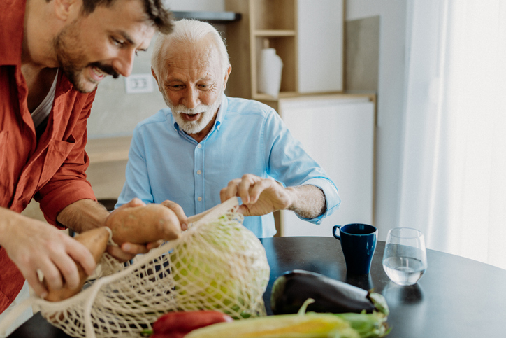Senior man enjoying activity with caregiver and fresh vegetables.