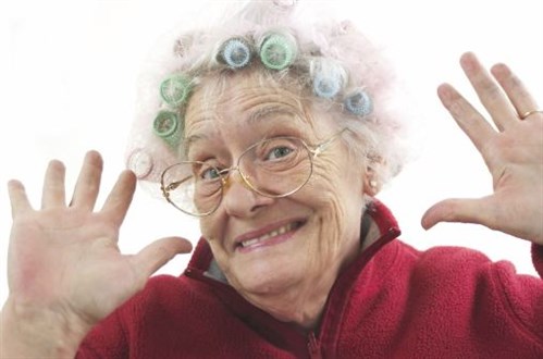 Elderly woman with curlers smiling and waving.