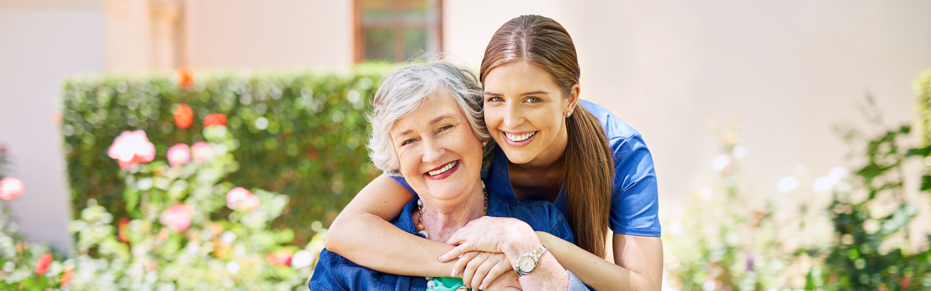 Smiling resident with caregiver in garden setting.