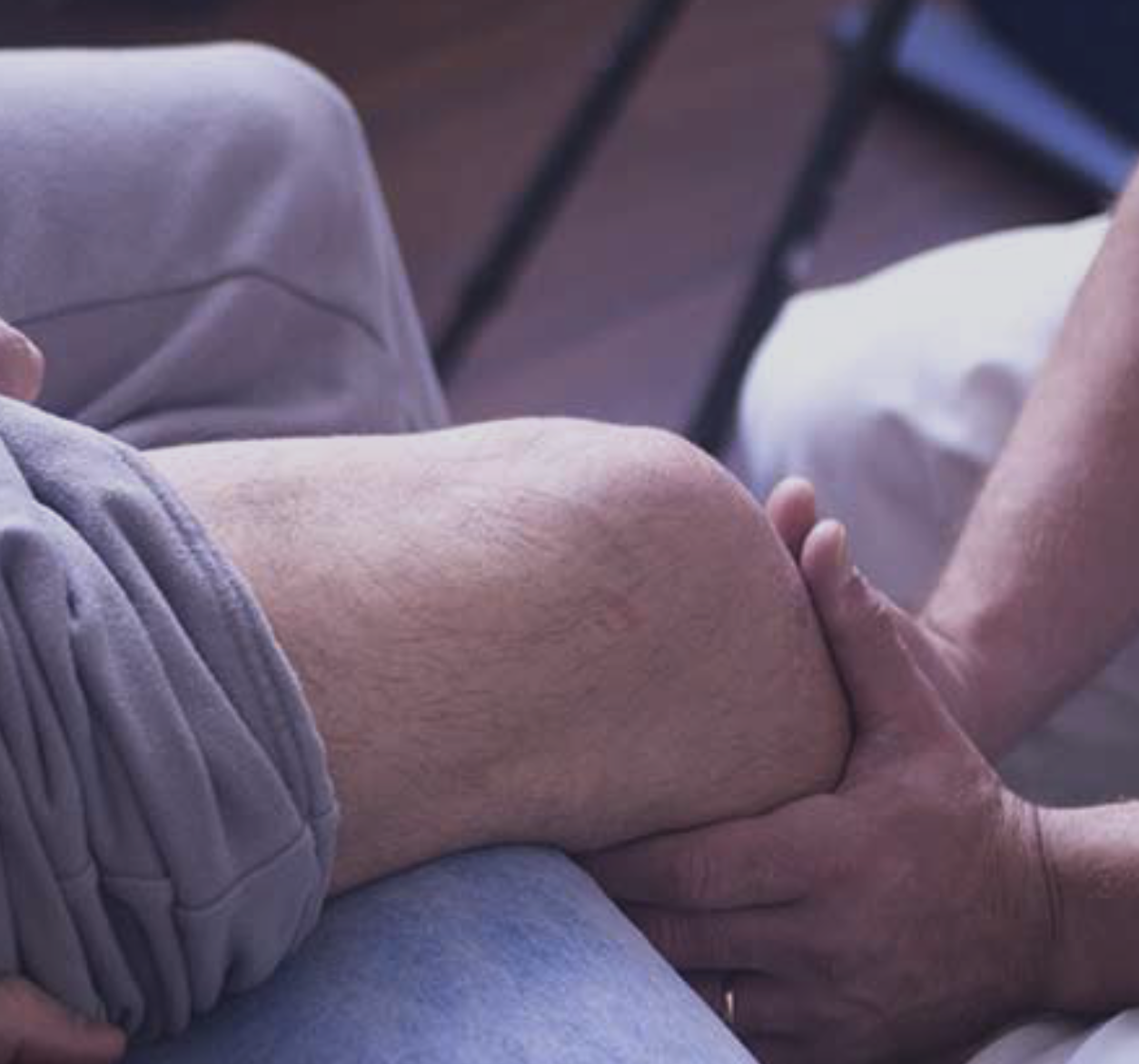 Hands providing therapeutic care to a knee