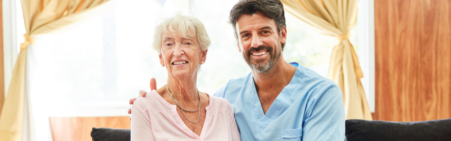 Healthcare worker with elderly resident smiling together.