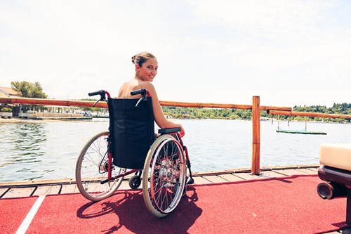 Smiling woman in a wheelchair by the water