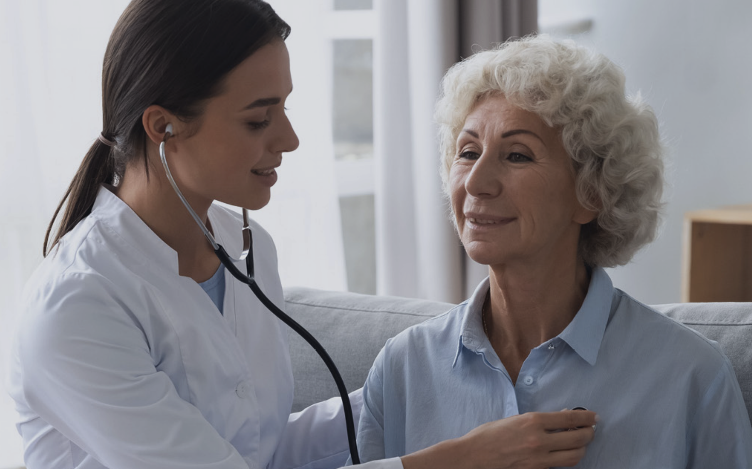 Nurse with a stethoscope examining a smiling senior woman