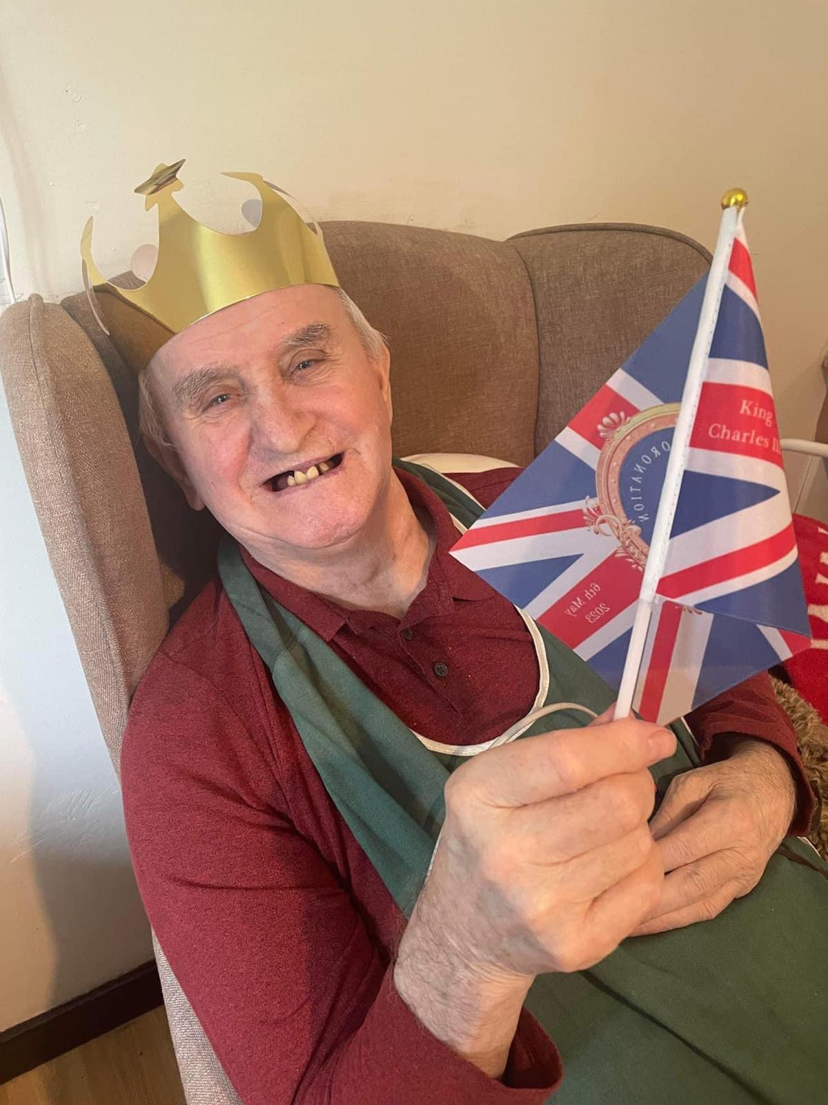 Elderly man in a crown holding a flag.