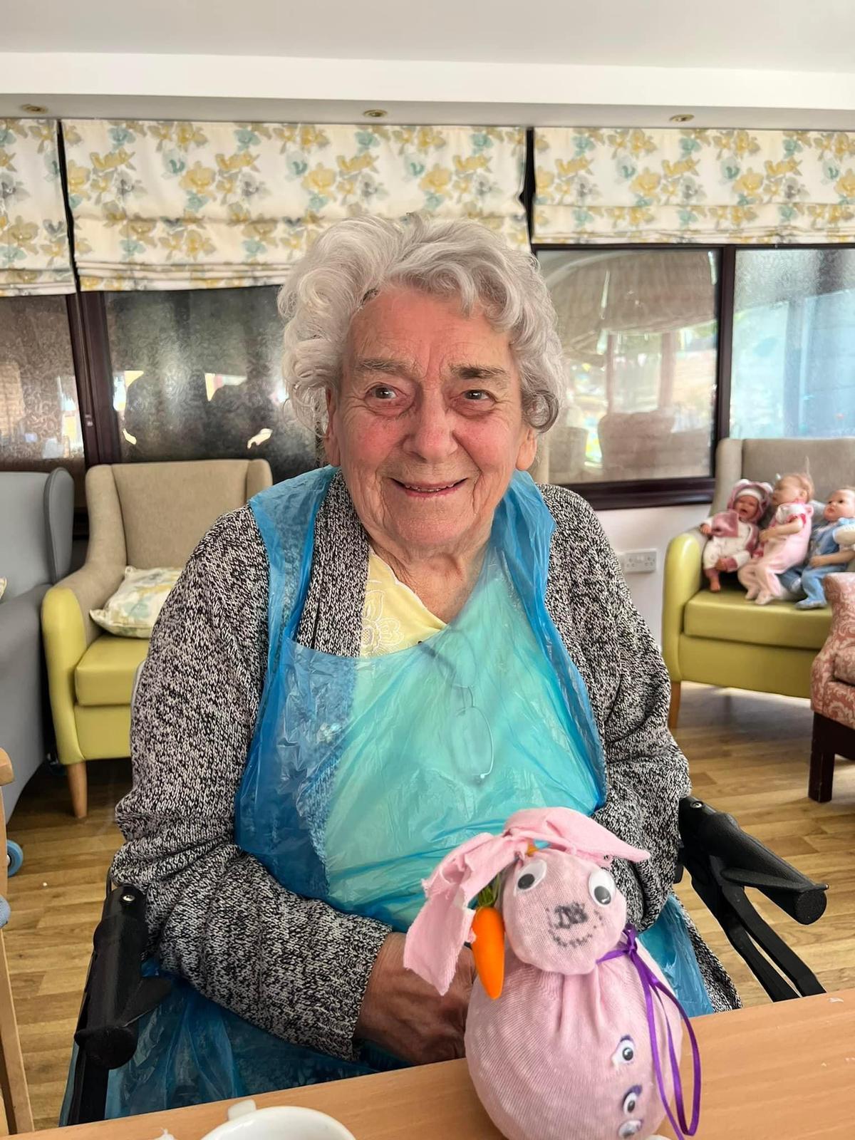 Smiling resident in a care facility with handmade toy.