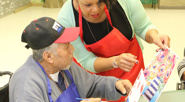 Resident participating in an art activity with staff guidance.