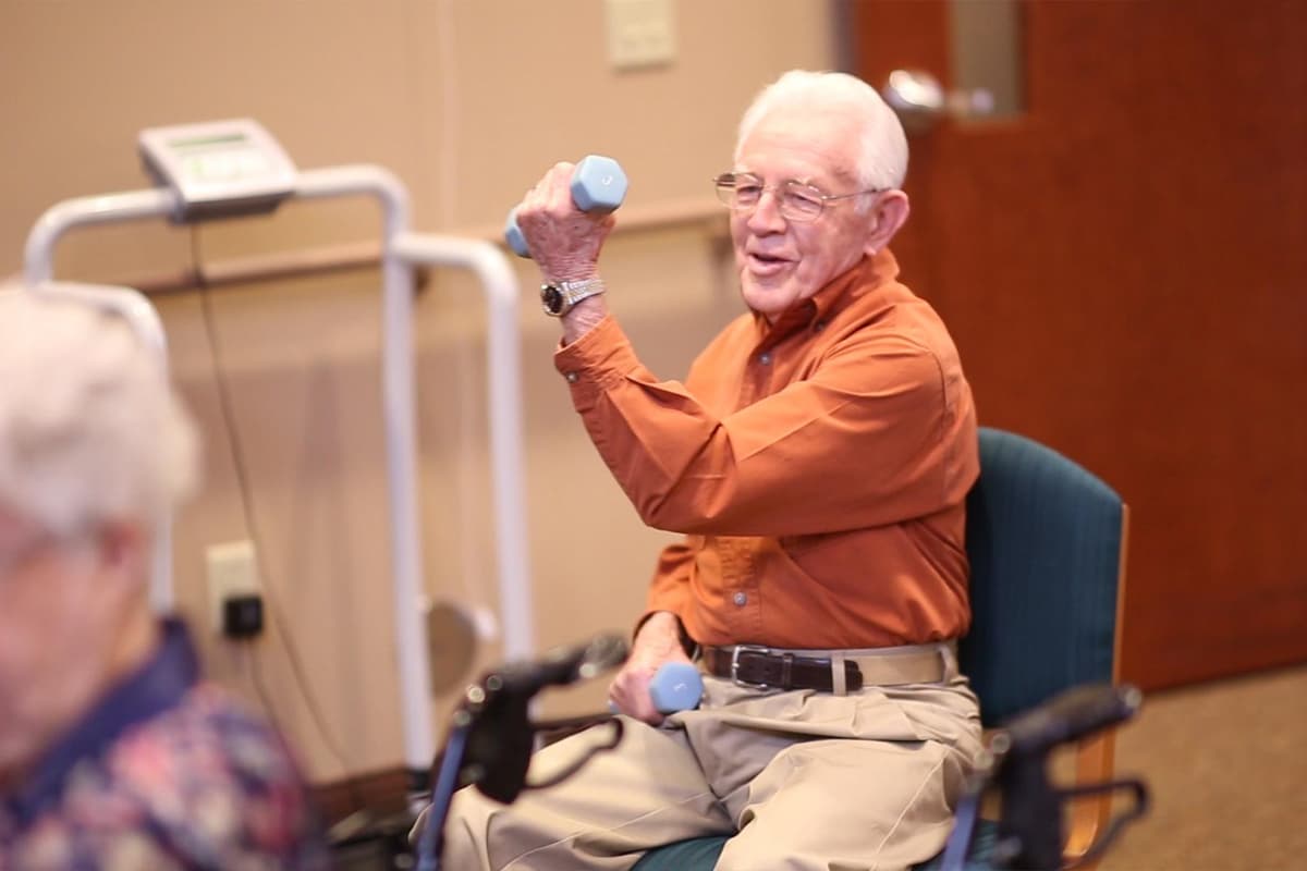 Senior resident exercising with dumbbell in activity room