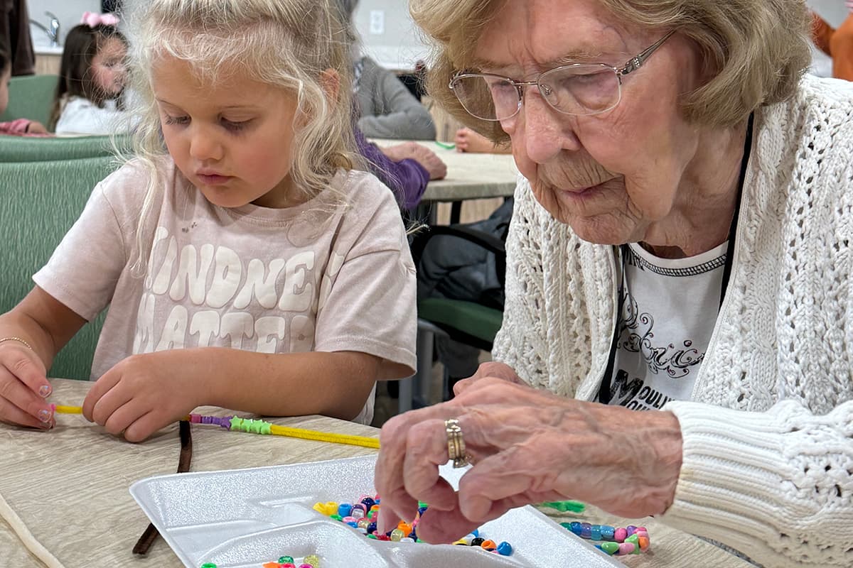 An elderly woman and a young girl engaged in an arts and crafts activity.