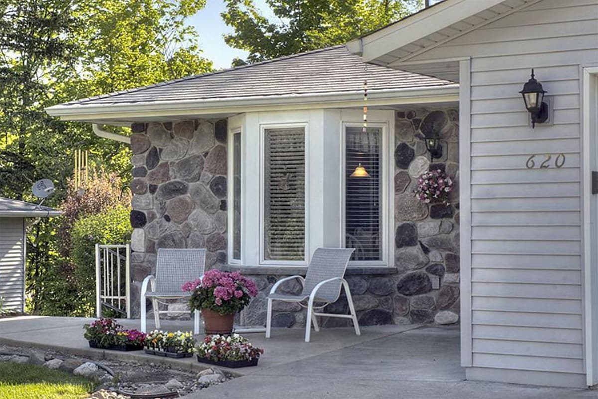 Entrance of a cottage with flowers and chairs outside