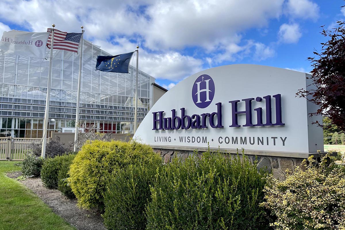 Hubbard Hill Village facility sign outside with flags
