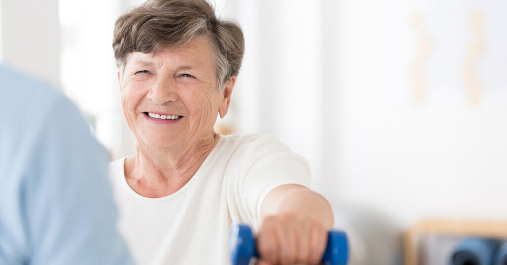 Elderly woman exercising with weights during therapy session