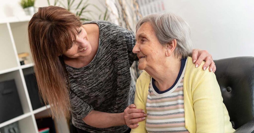 A caregiver smiling with a senior resident in a warm setting