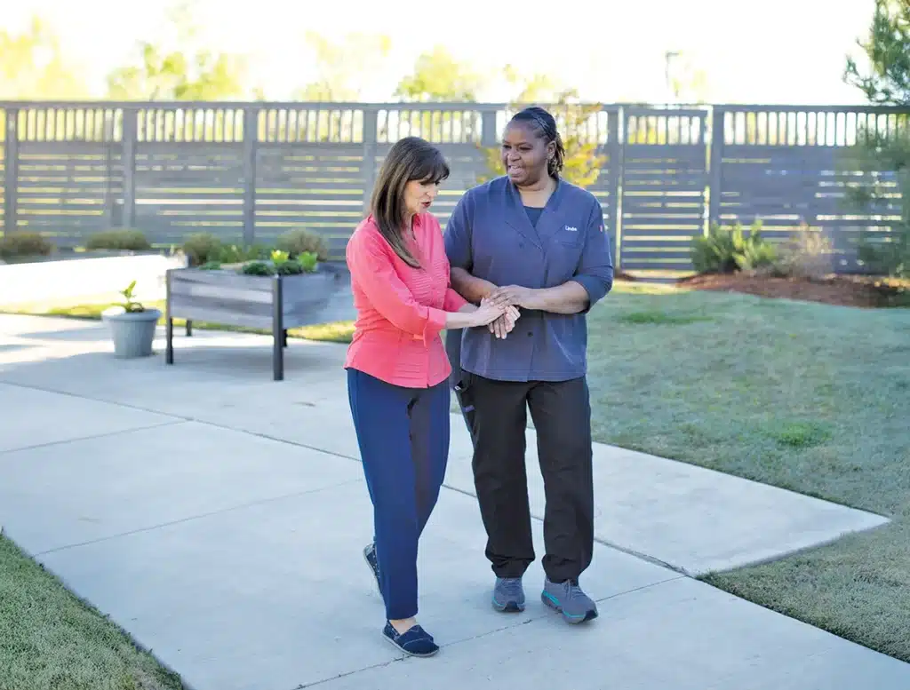 Staff assisting a resident on a pathway outside