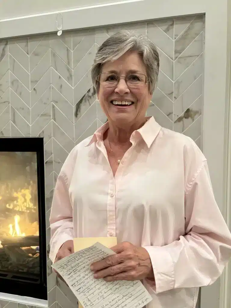 Senior resident smiling by the fireplace