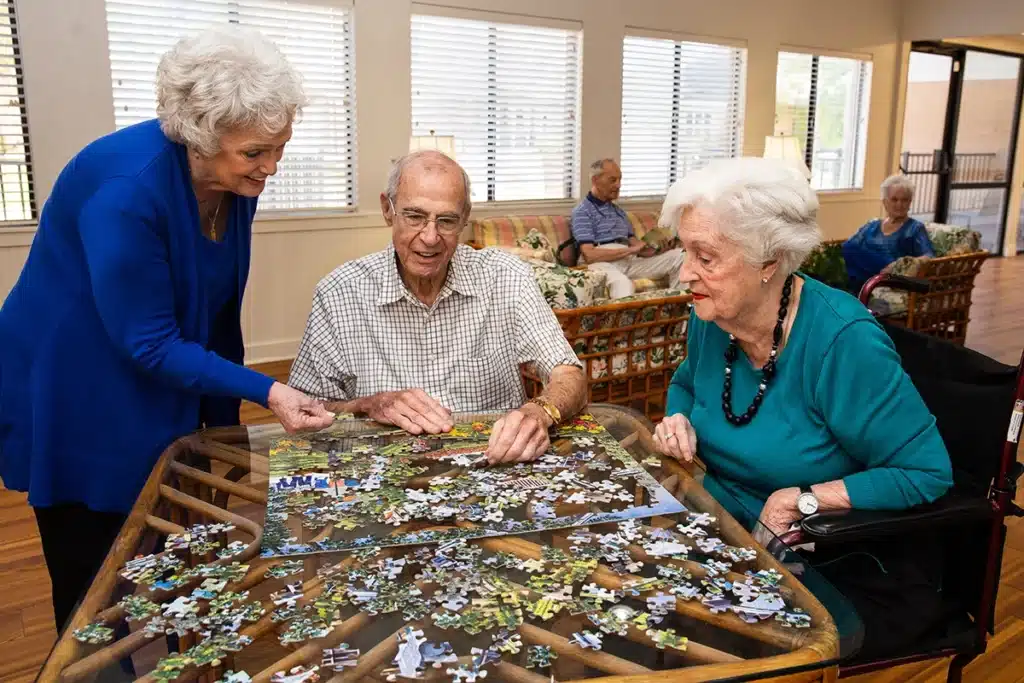 Residents and staff working on a puzzle in a common area