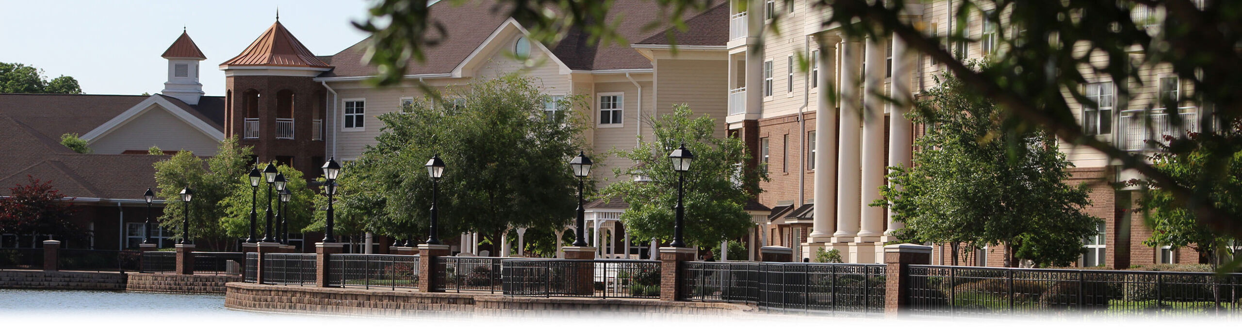 Outdoor view of a senior living facility with trees and light posts