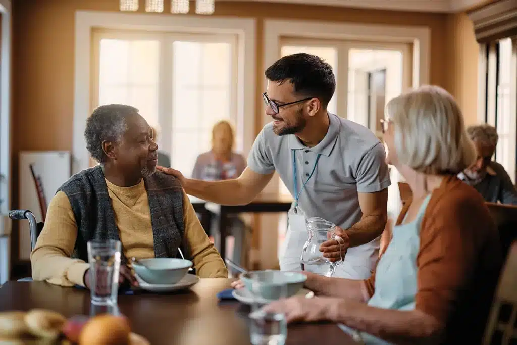 Residents enjoying a meal with staff in a dining room