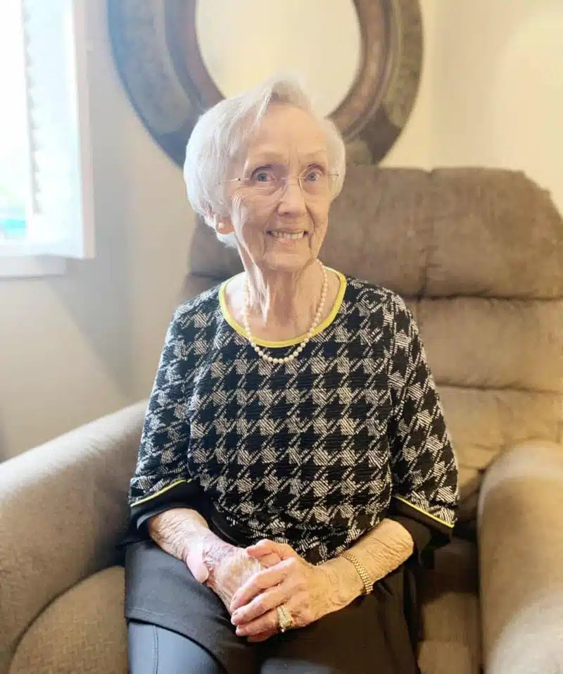 An elderly woman smiling in a cozy armchair