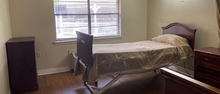 Brightly lit private resident room with a bed and furniture