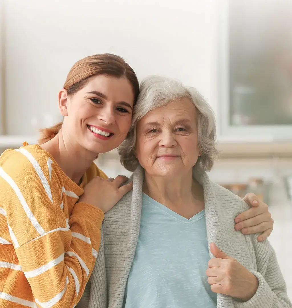 A caregiver and a resident smiling together in a bright room