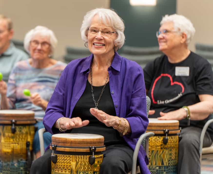 Elderly residents engaging in a drumming activity.