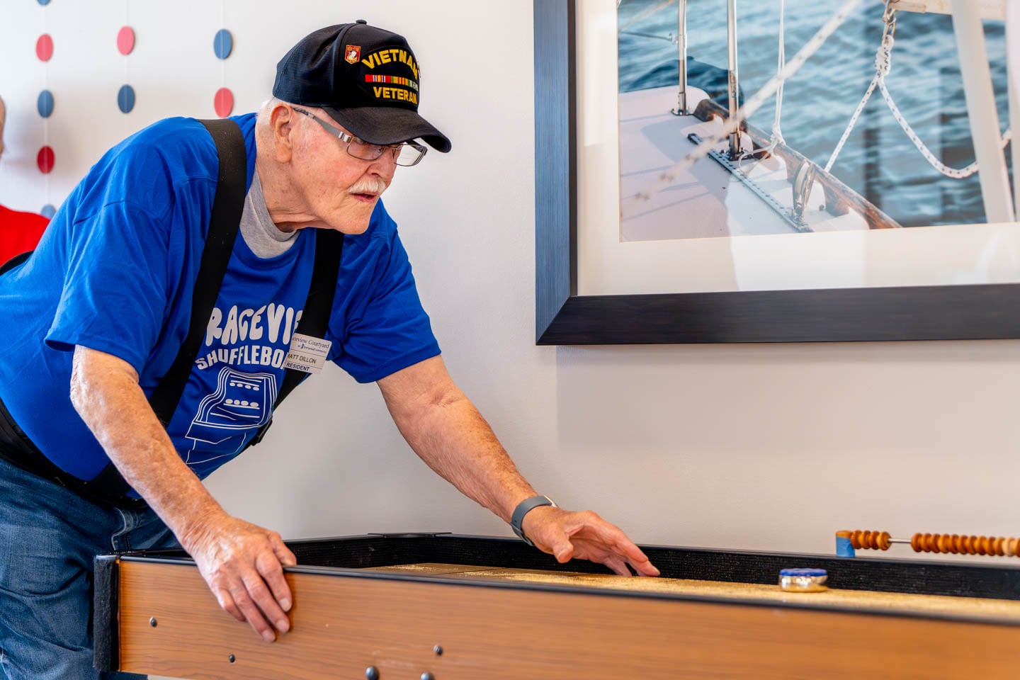 Senior playing shuffleboard indoors at the facility.