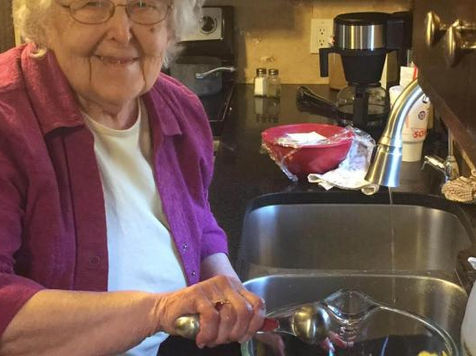 Elderly woman happily cooking in a kitchen.