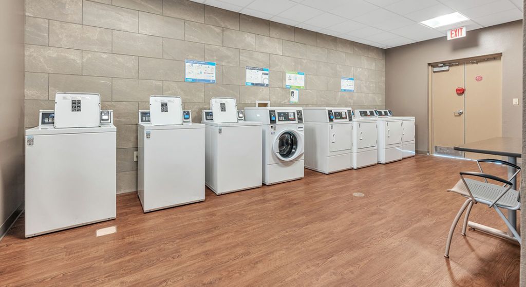 Laundry room with multiple washing machines and a dryer.