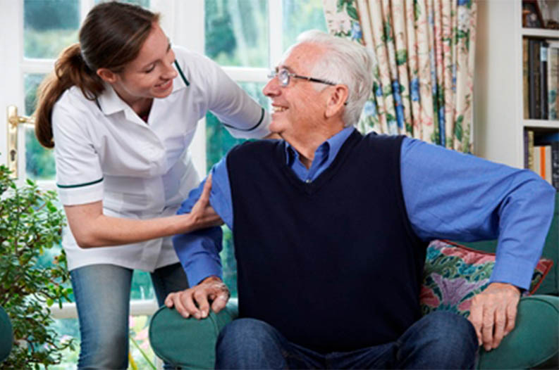Caregiver assisting an elderly resident in a cozy living area.