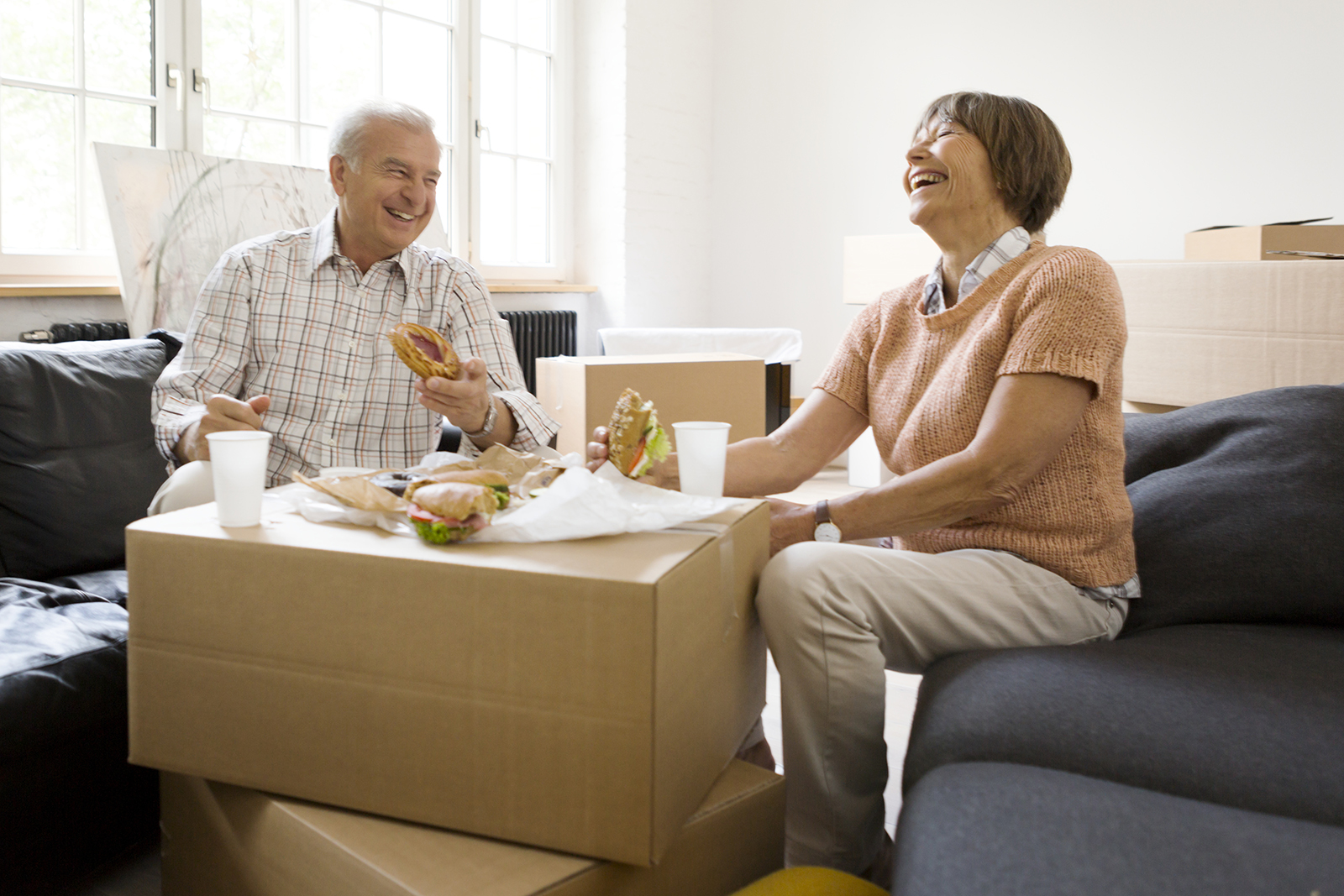 Two seniors enjoying a meal and laughing together.